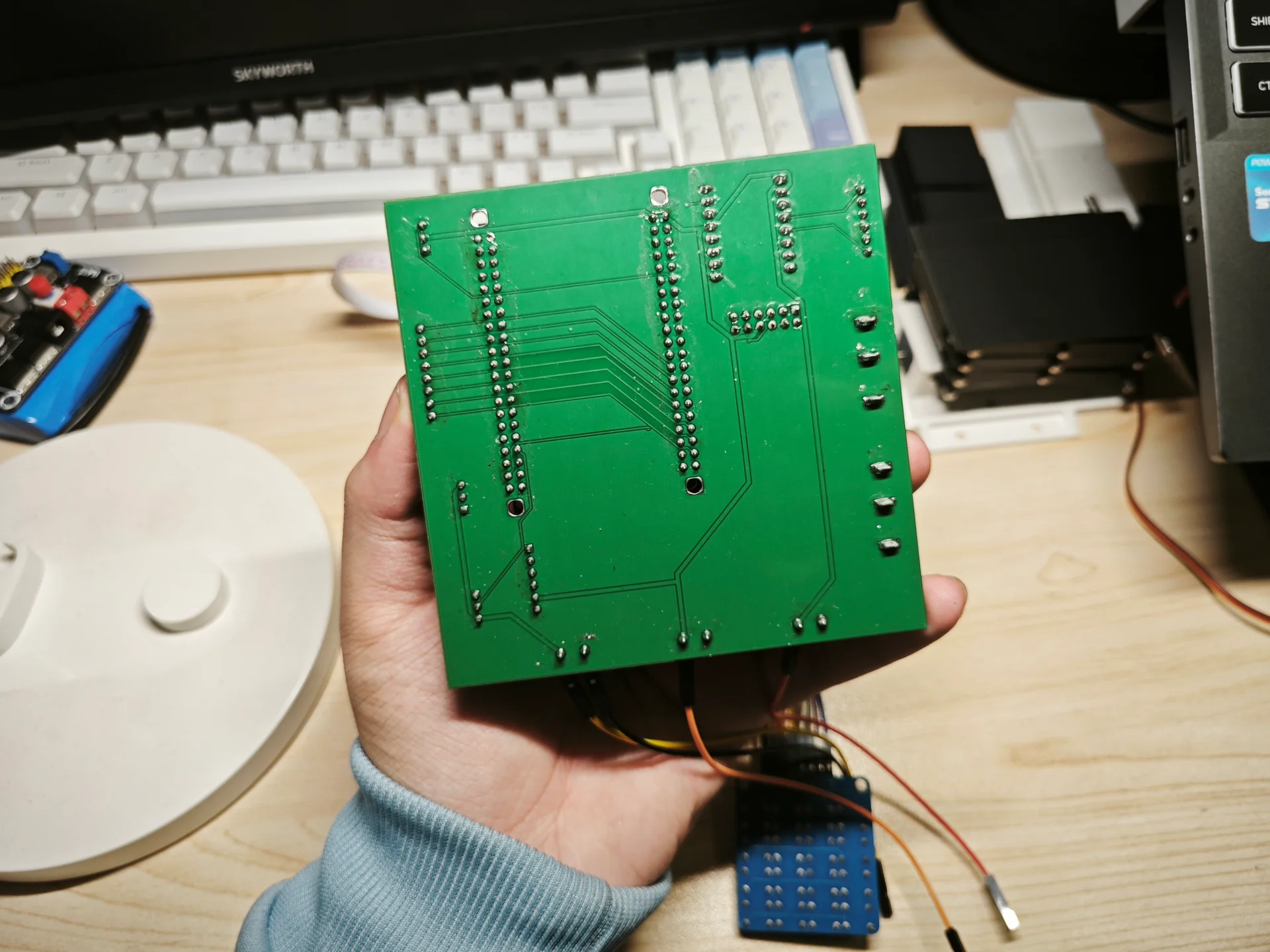 手持绿色电路板连接线缆背景办公桌